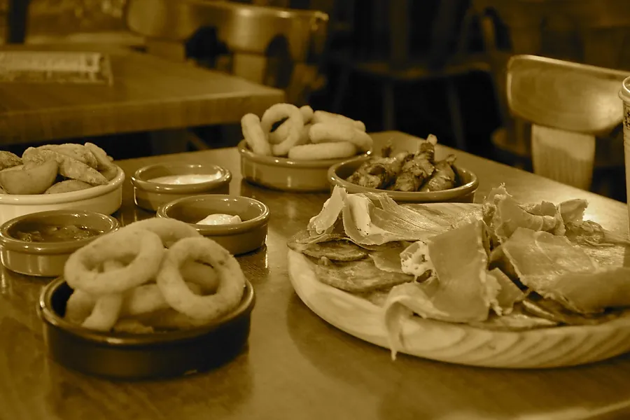 Tapas sur une table : calamars, charcuterie, petites sauces