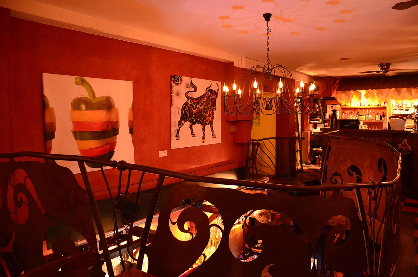 La salle du Cocolobo : murs rouges, lustre à bougies et rambarde en fer forgé